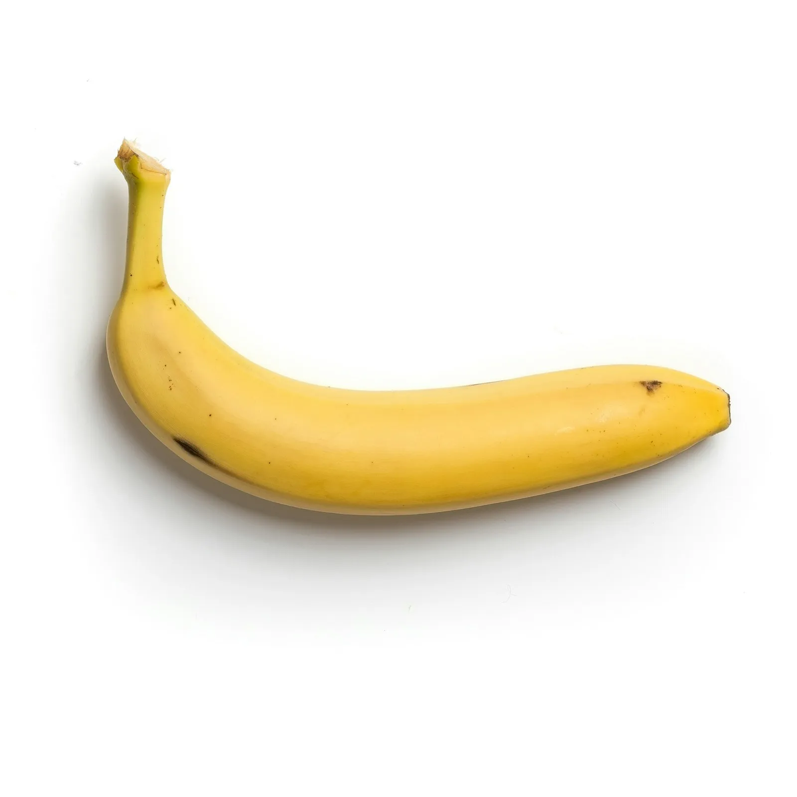 Banana madura inteira com casca amarela sobre fundo branco, fonte de potássio associada à câimbra