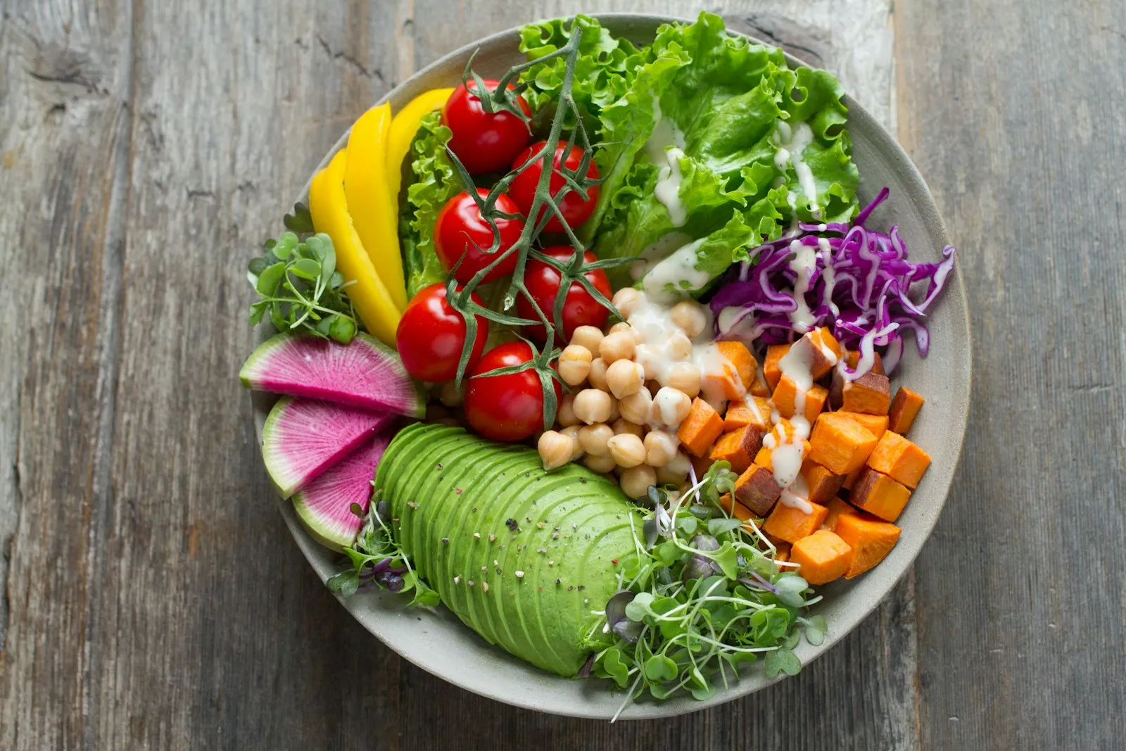 Salada colorida em tigela com folhas, tomate, grão-de-bico, abacate, batata-doce e molho leve