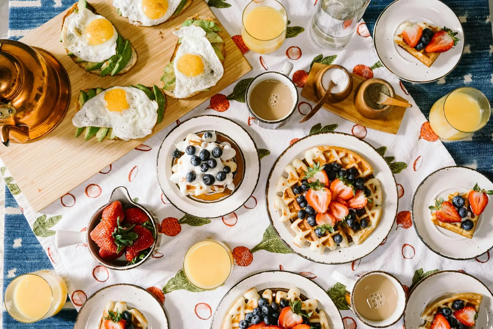 Mesa de café da manhã de final de semana com waffles, frutas, ovos, café e sucos