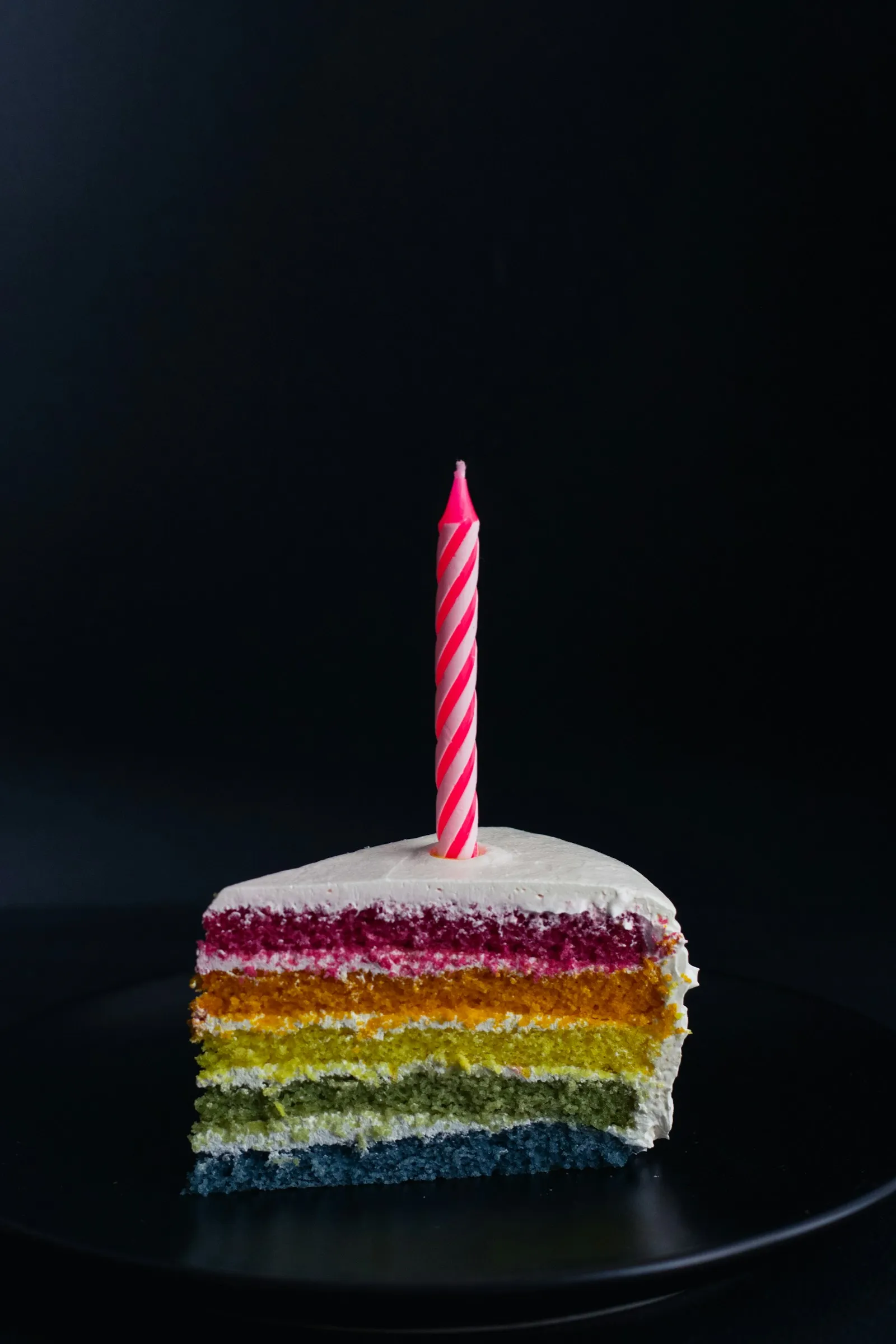 Fatia de bolo colorido em camadas com vela de aniversario rosa, para a vontade de bolo