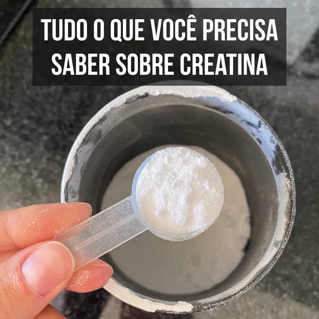 Mão segurando dosador com creatina em pó branco sobre pote do suplemento